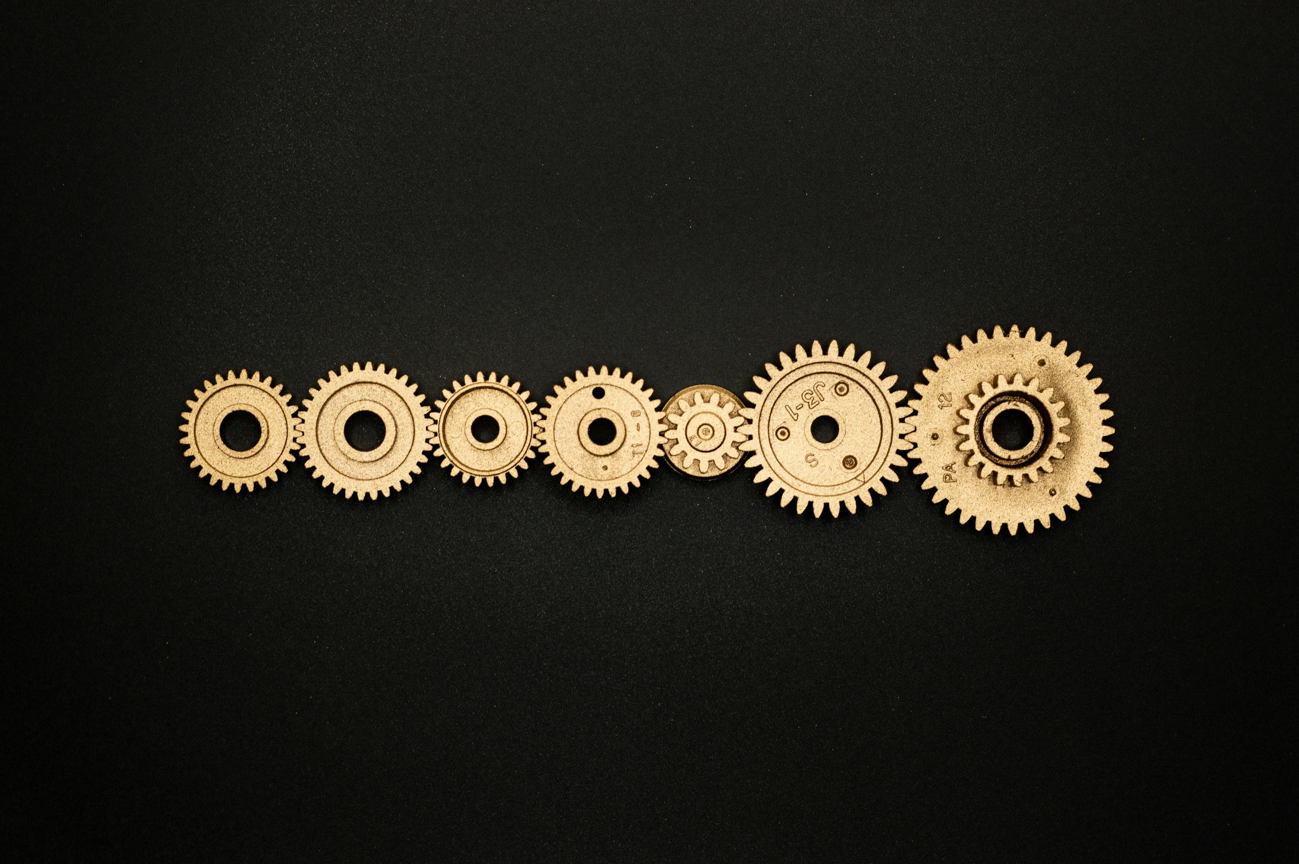 An artistic arrangement of golden gears on a dark backdrop, symbolizing mechanics and cooperation.